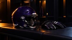 Dunkelvioletter Football-Helm und Handschuhe auf einer leeren Umkleidebank